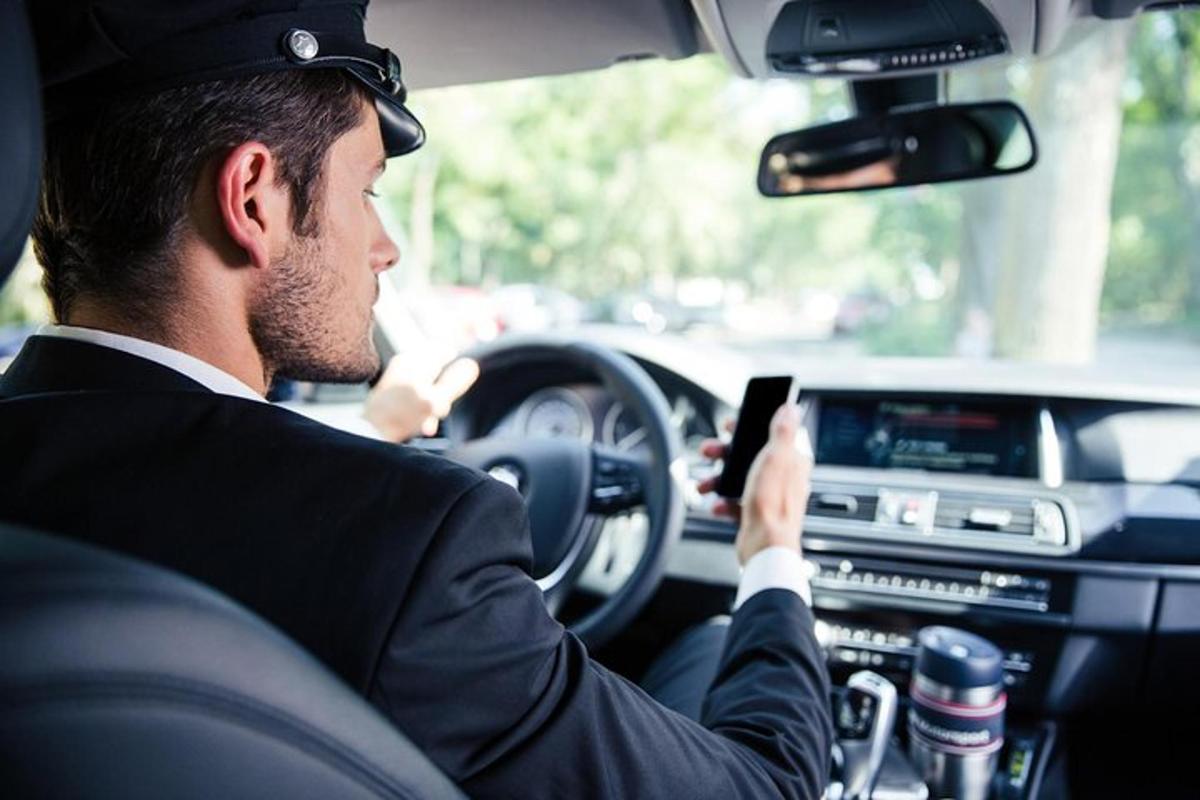 um homem dirigindo um carro enquanto olha para um celular