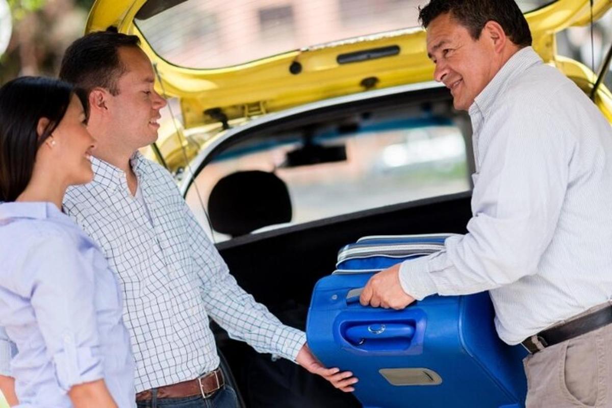 dois homens e uma mulher segurando uma mala na parte de trás de um carro