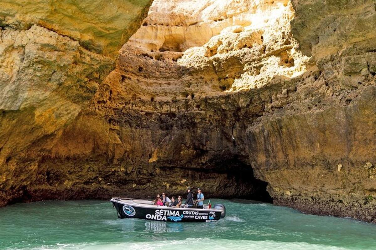 Un grupo de personas en un barco frente a una cueva.