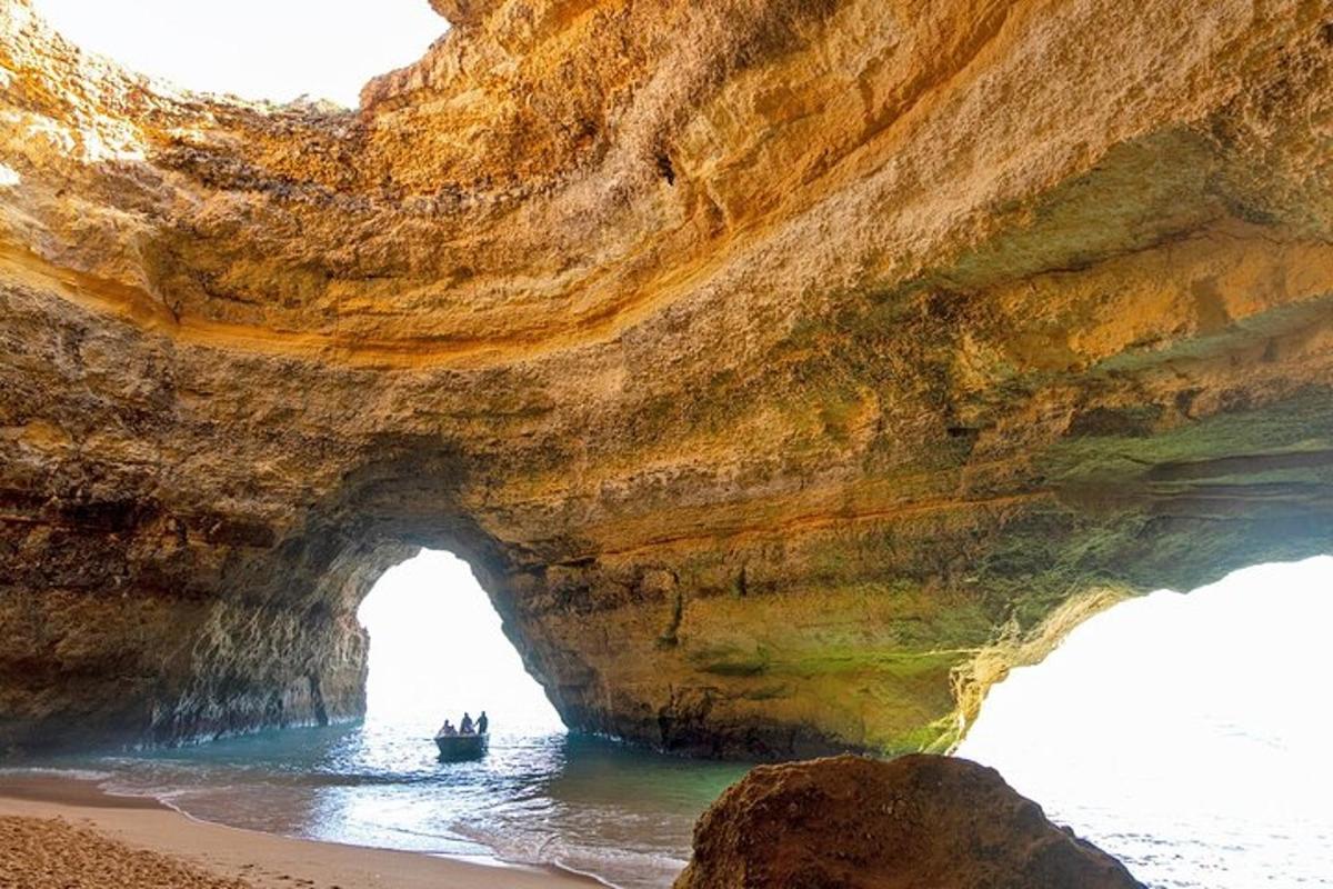 a cave on the beach with a boat in the water
