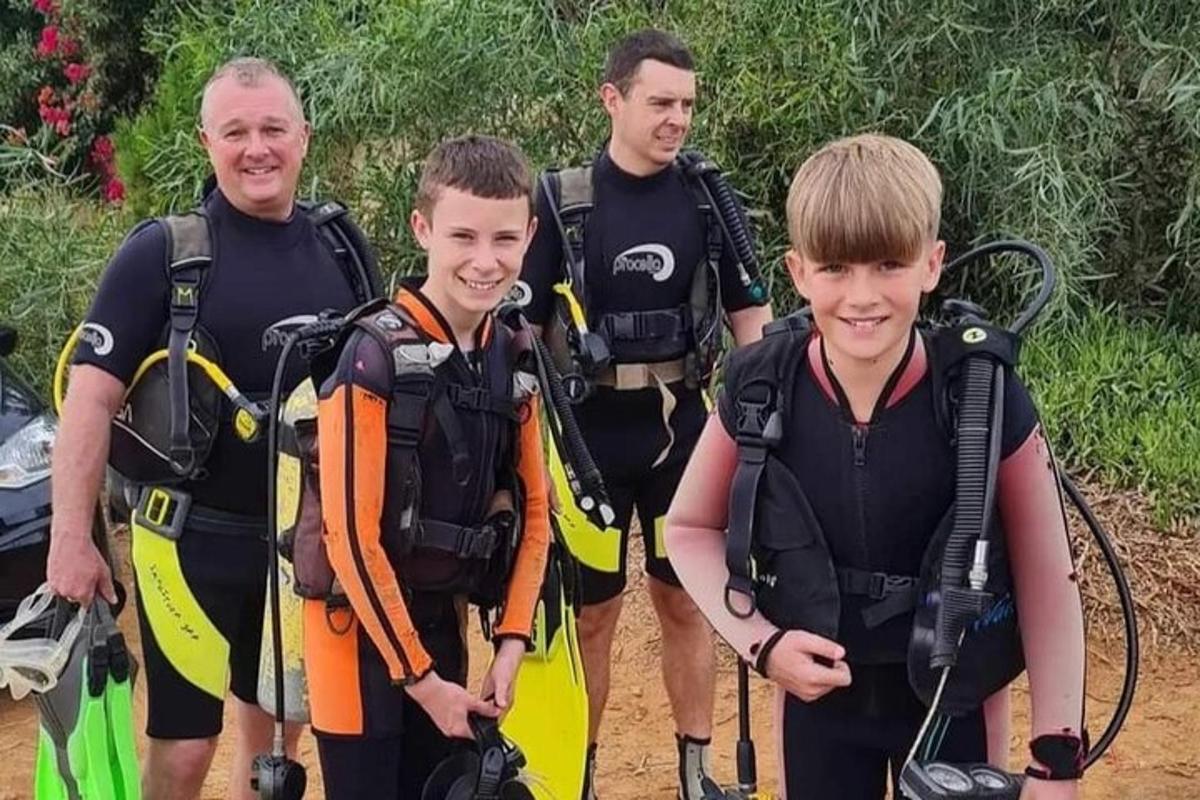 un grup de oameni în echipament de scufundări care pozează pentru o fotografie