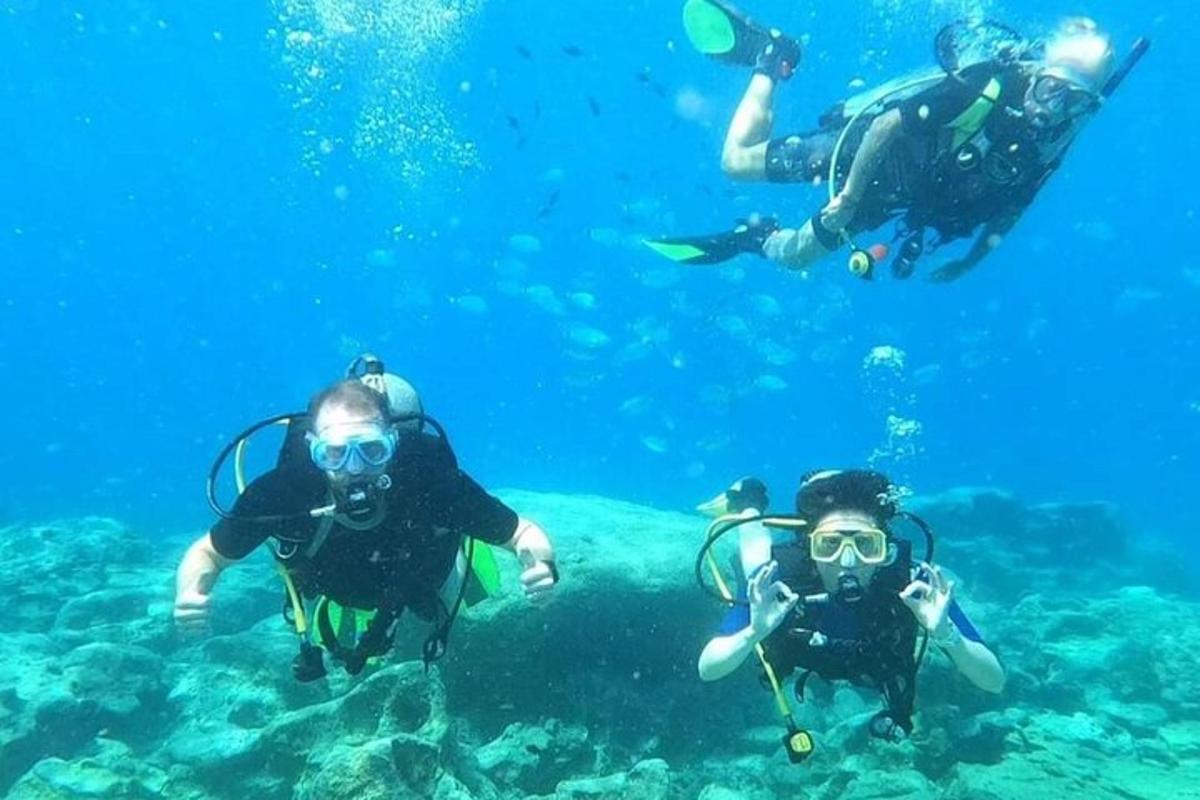 tiga orang sedang menyelam skuba di lautan