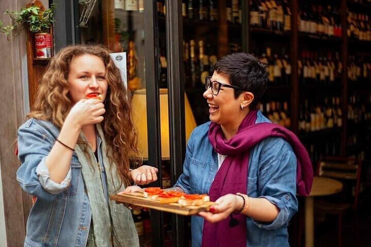 Dvě ženy jedí pizzu a jedna drží tác s pizzou