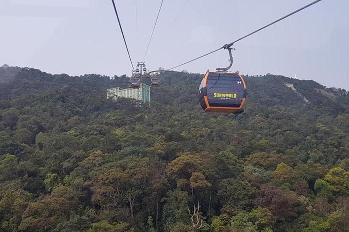 an orange cable car flying over a forest