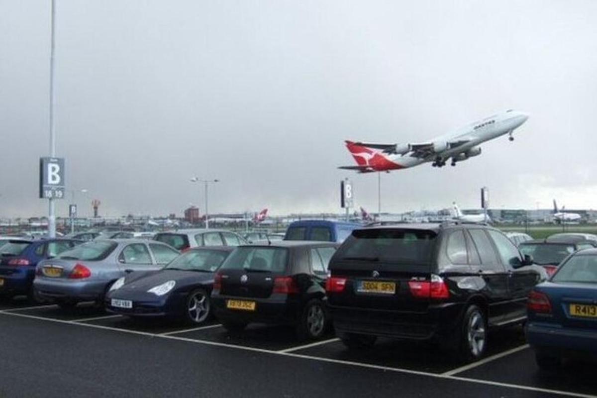 Un montón de coches aparcados en un estacionamiento con un avión.