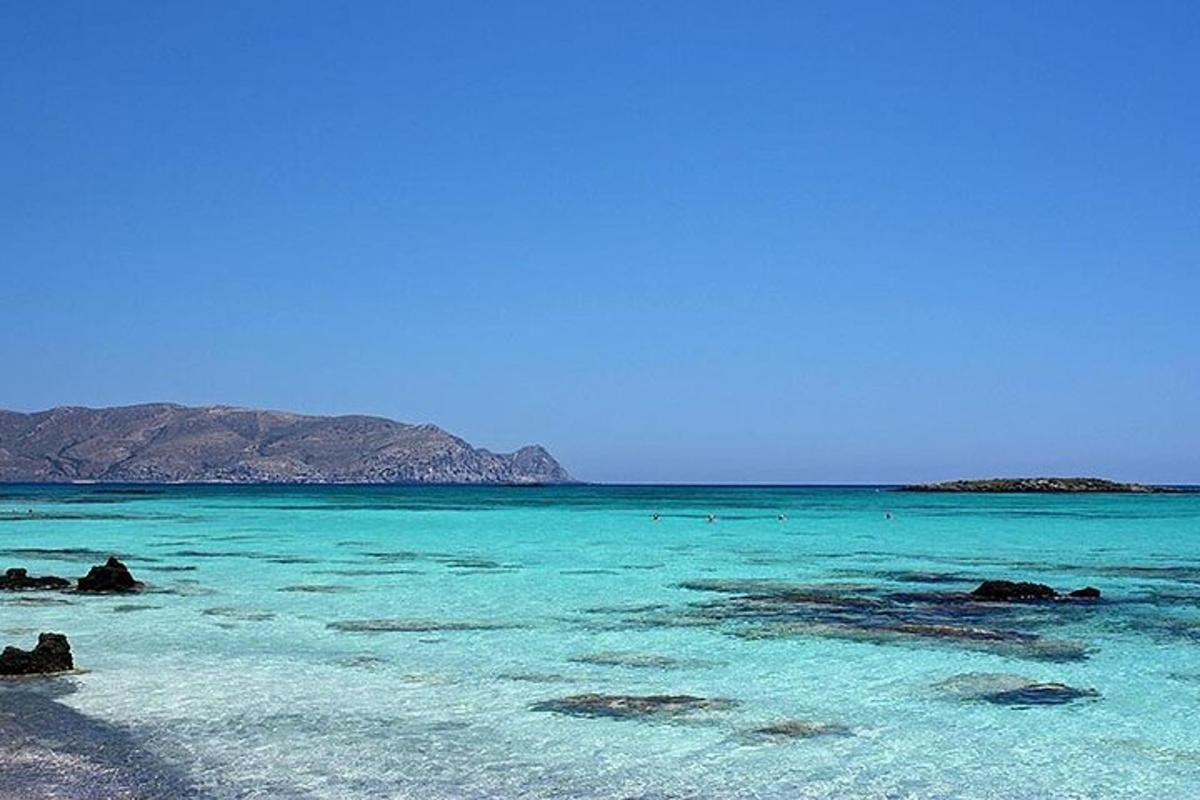 a beach with blue water and mountains in the background