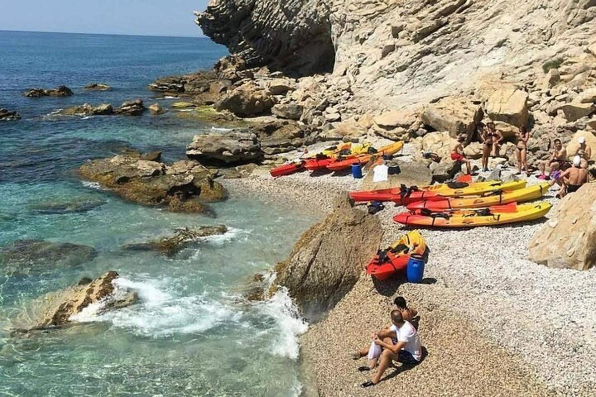 grupa ludzi na kamienistej plaży z łodziami