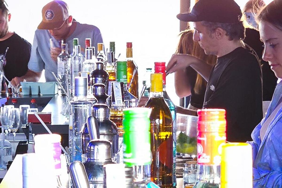 skupina lidí sedících u baru s lahvemi alkoholu