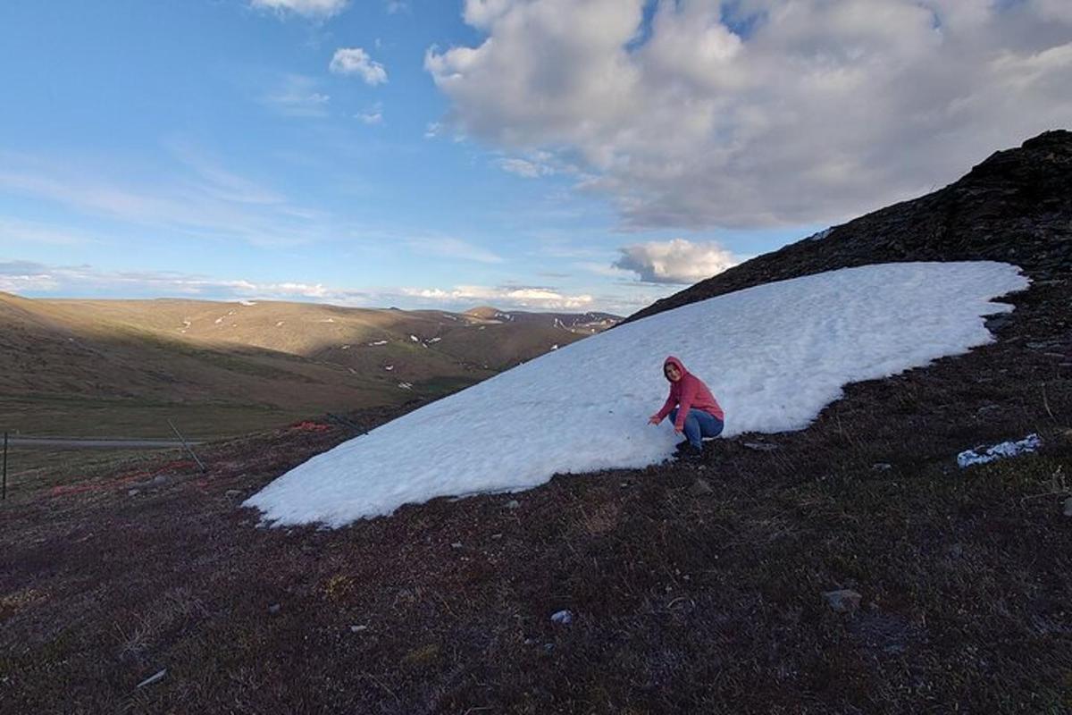 una persona in piedi in cima a una collina coperta di neve