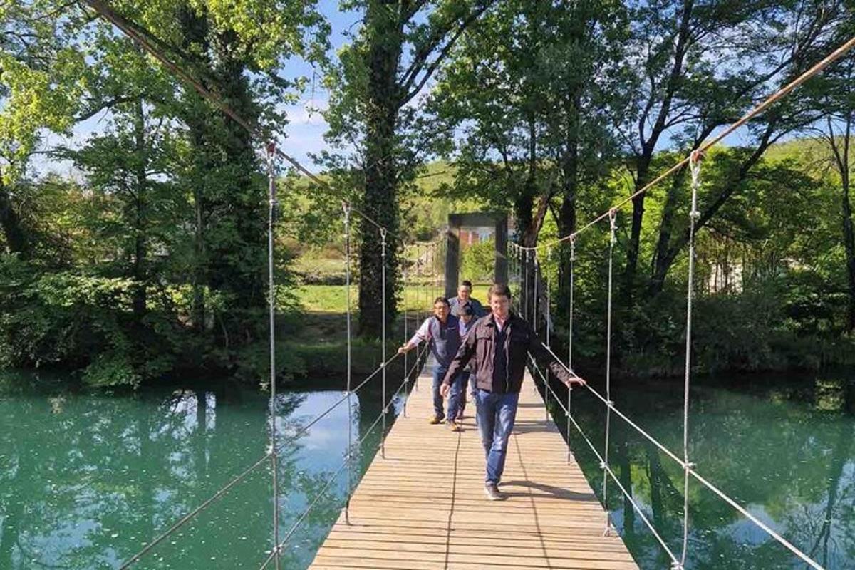 tres homes caminant per un pont penjant sobre un riu