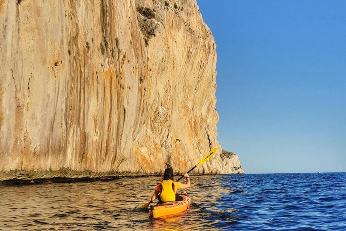 una persona en un kayak en el agua cerca de un acantilado