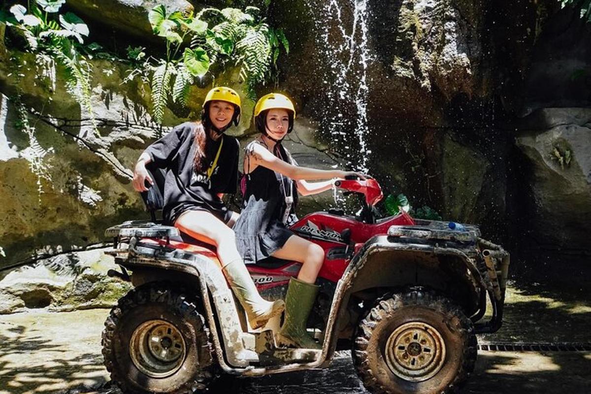 two girls riding on a atv in front of a waterfall