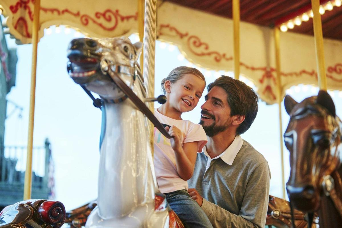 a man and a young girl riding on a carousel