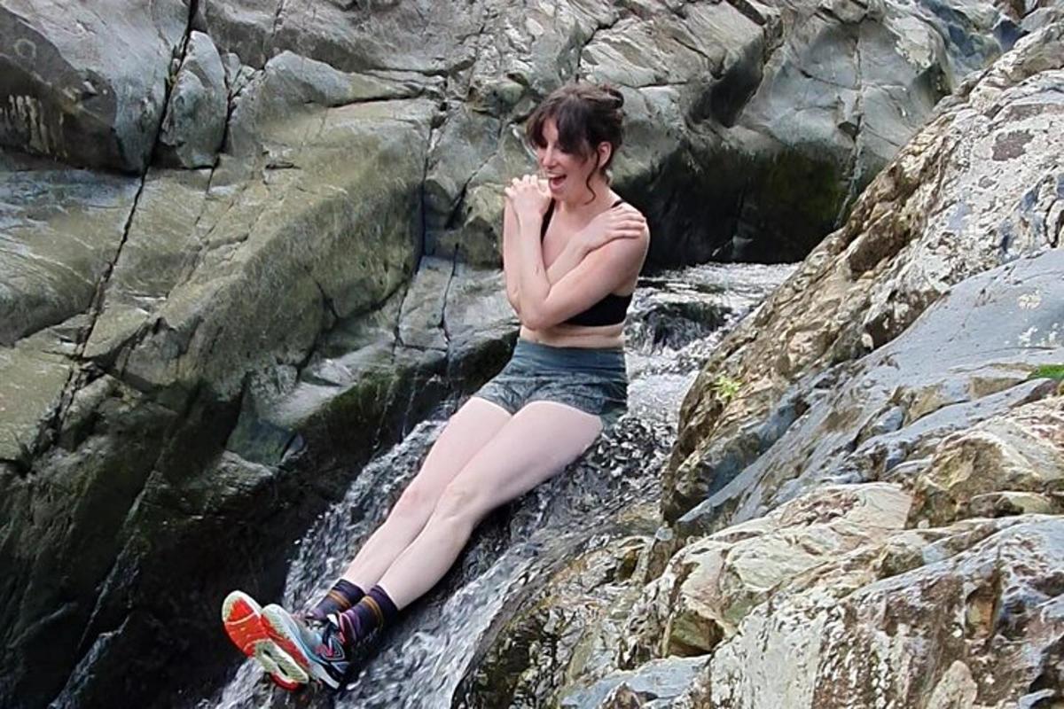 a woman sitting on a rock in a waterfall