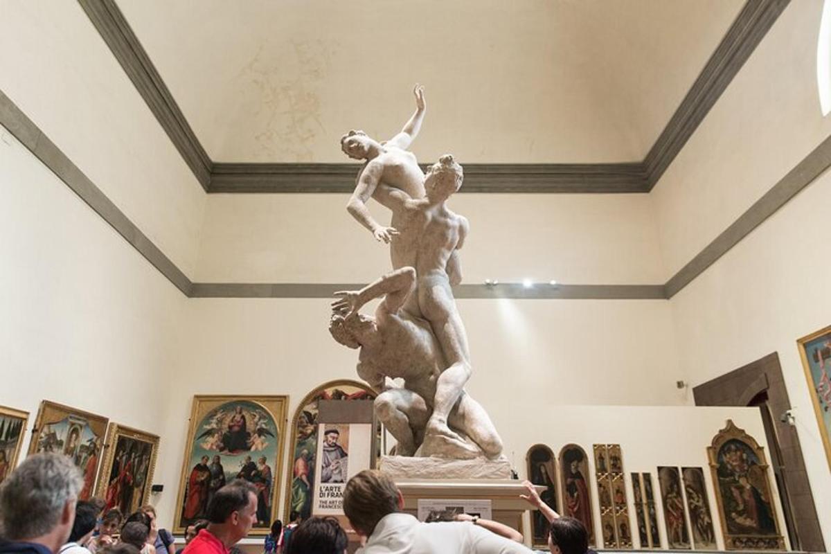 una folla di persone che guarda una statua in un museo