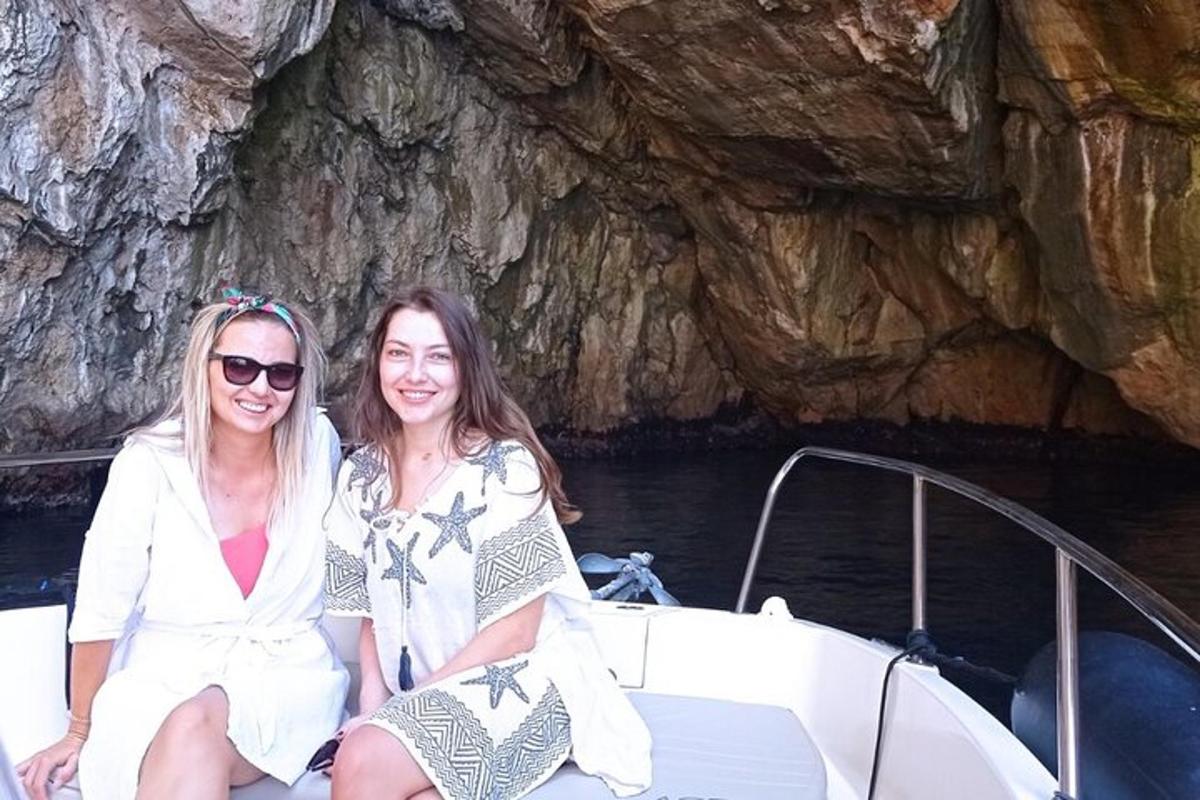 zwei Frauen sitzen auf einem Boot vor einer Höhle