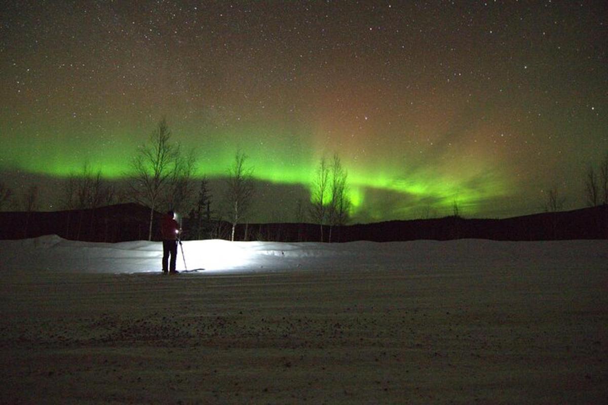 eine Person, die auf Skiern unter dem Nordlicht steht