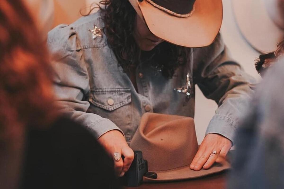 Una mujer con un sombrero de vaquero mirando dentro de un bolso.