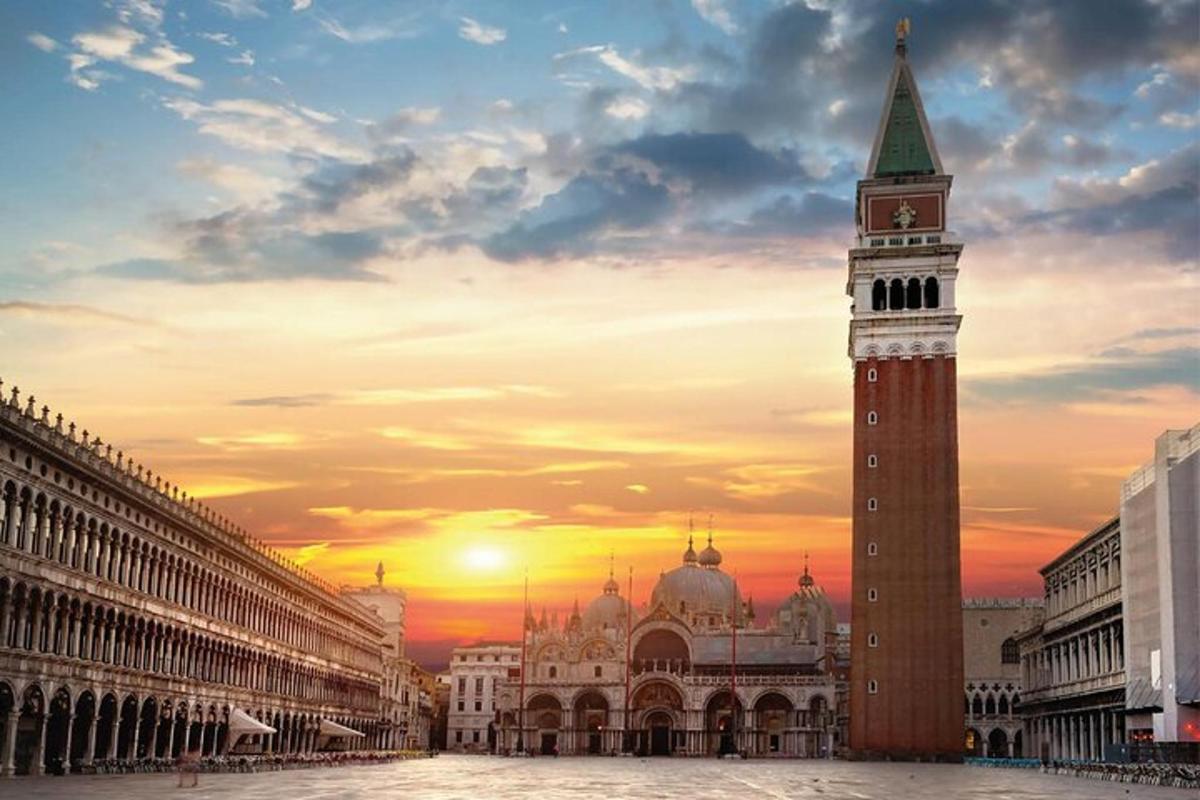 una torre dell'orologio in una città con un tramonto sullo sfondo