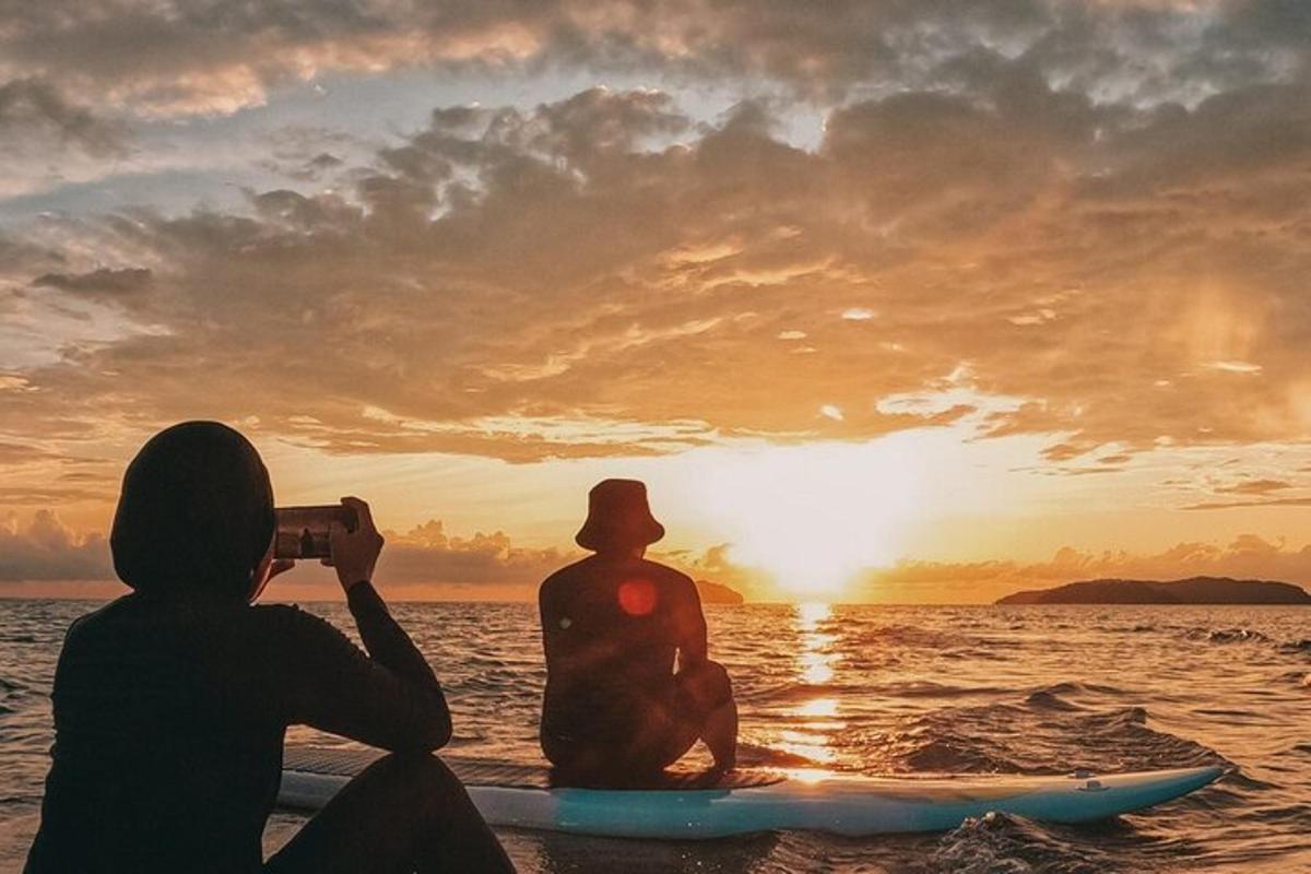 una dona fent una foto d'un home sobre una taula de surf a l'oceà