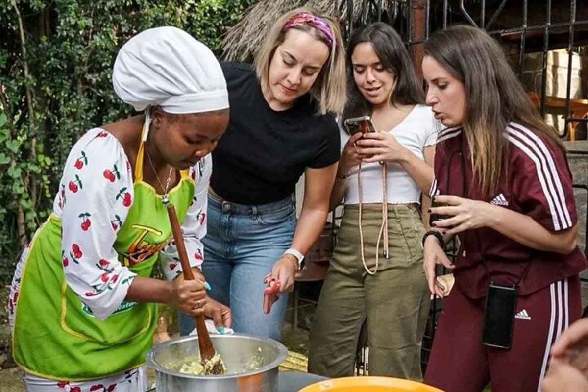 Un grupo de mujeres de pie alrededor de una olla de comida.