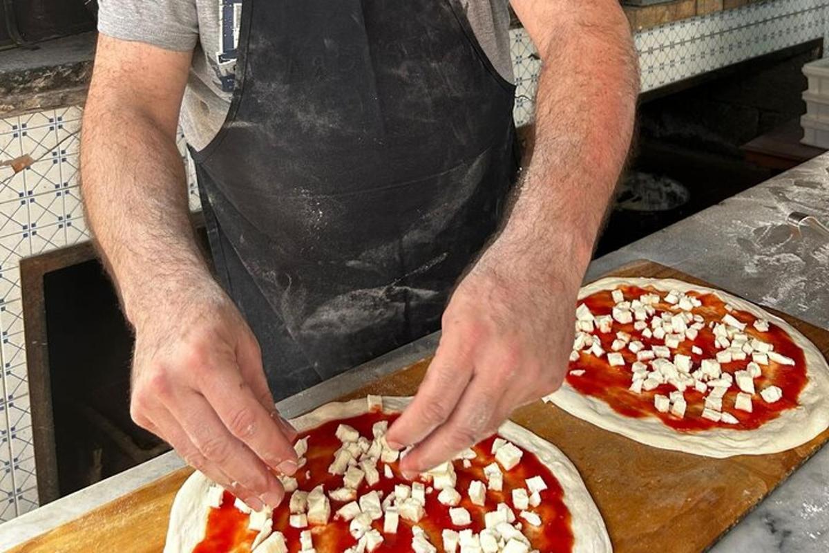a man making two pizzas on a cutting board