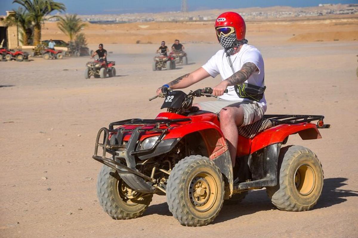 un home que condueix un quad per la platja