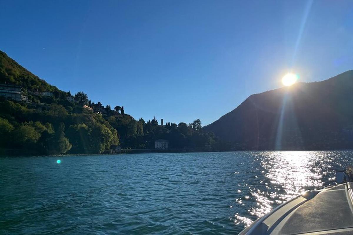 un vaixell en un llac amb el sol brillant sobre l'aigua