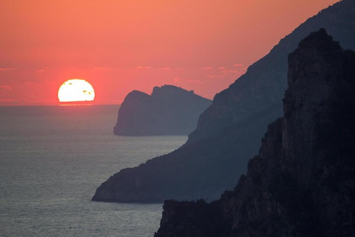 un apus de soare peste ocean cu un munte