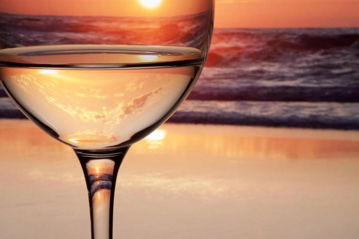 un pahar de vin pe plajă cu apusul soarelui