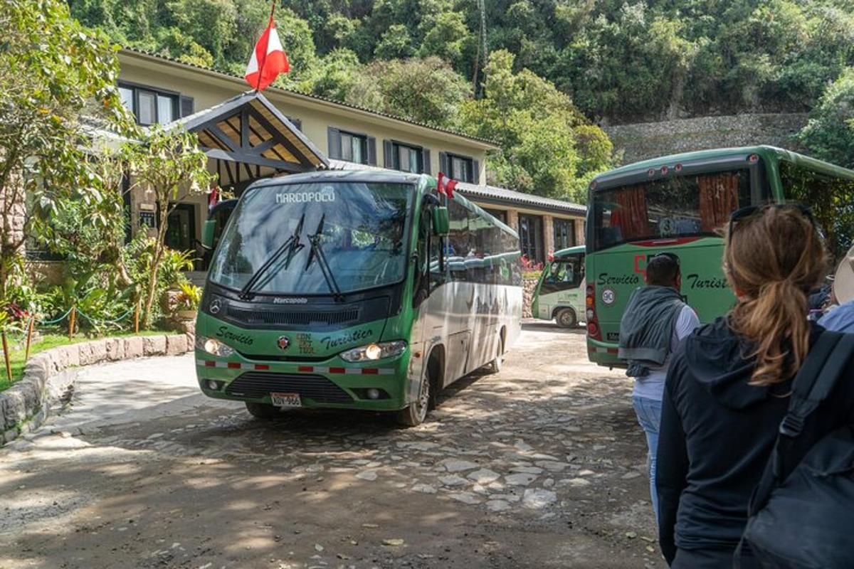 un grup de persones al costat de dos autobusos
