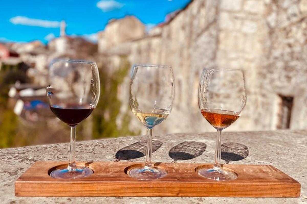 trei pahare de vin așezate pe o placă de tăiere din lemn