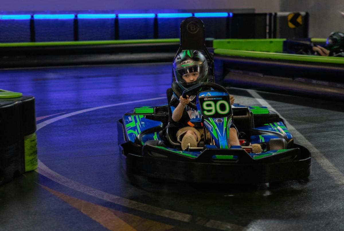 dítě jedoucí v autíčku v bowlingové dráze