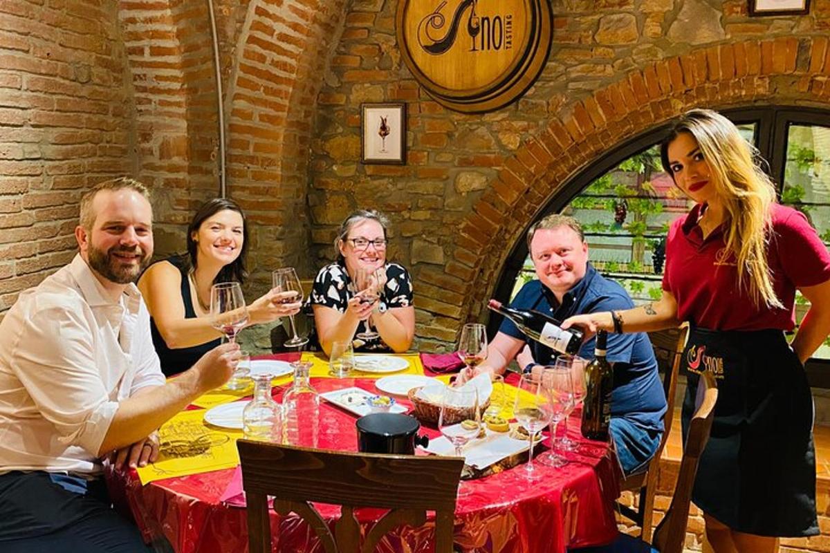 un grup de oameni așezați în jurul unei mese cu pahare de vin