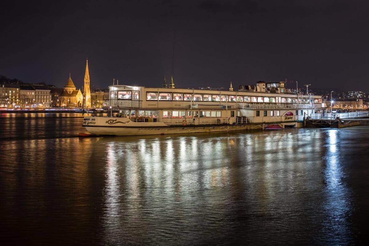 a boat in the water in front of a building at night