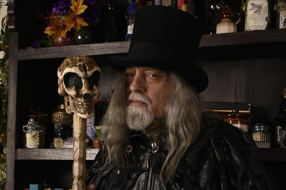 a man wearing a hat holding a skull and a wand