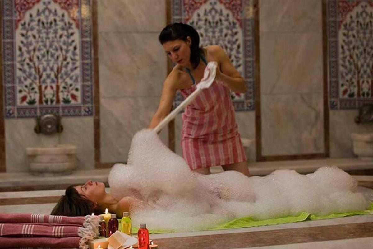 seorang wanita berdiri di atas seorang wanita berbaring di dalam tab buih
