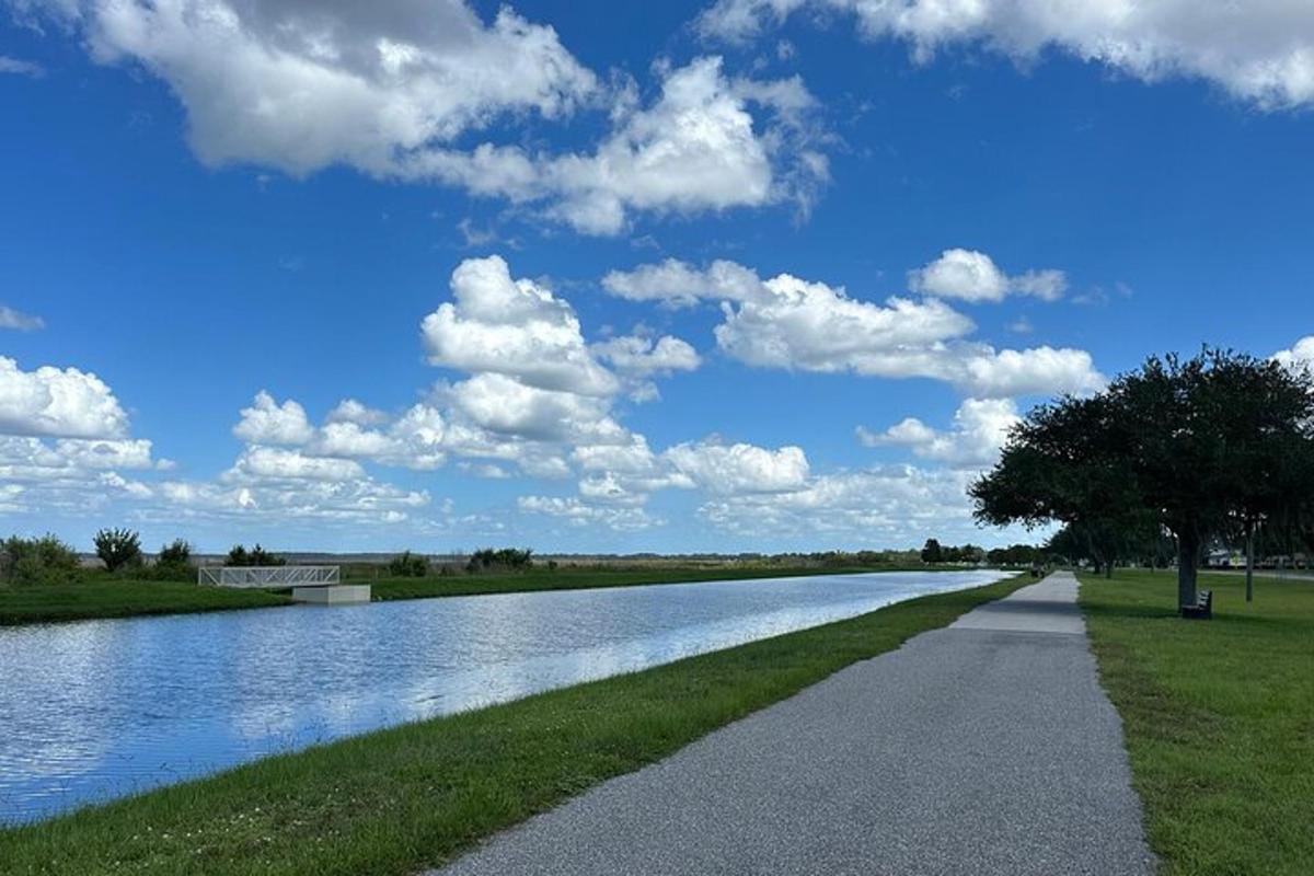 un sentiero lungo un fiume con un cielo nuvoloso