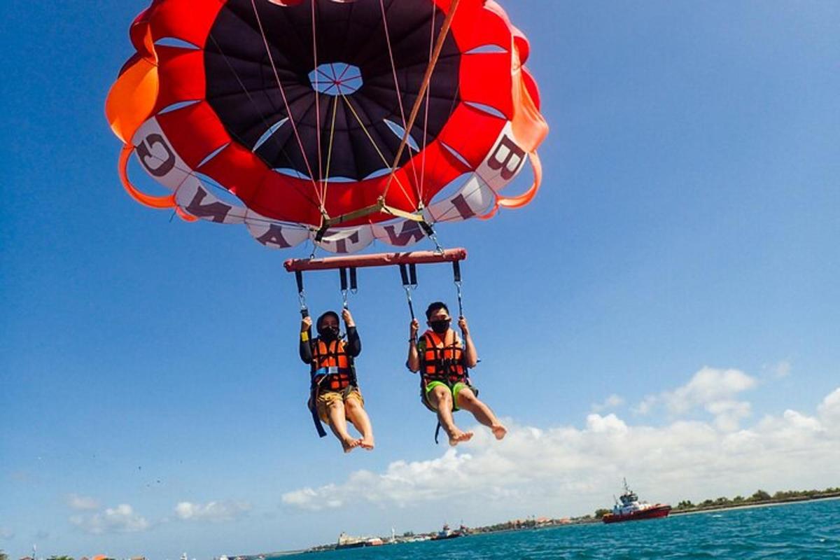 two people are hanging from a parachute in the water