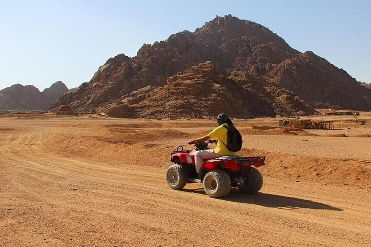 seseorang yang menunggang basikal quad di padang pasir