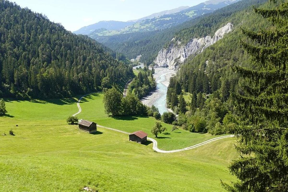 Un campo verde con casas y un río en un valle.