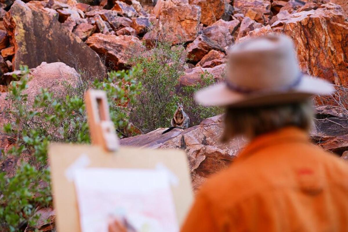 a man wearing a cowboy hat looking at a bird