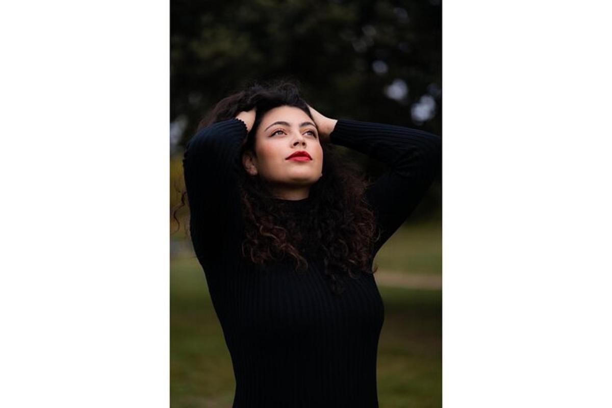 a woman in a black dress leaning against a wall