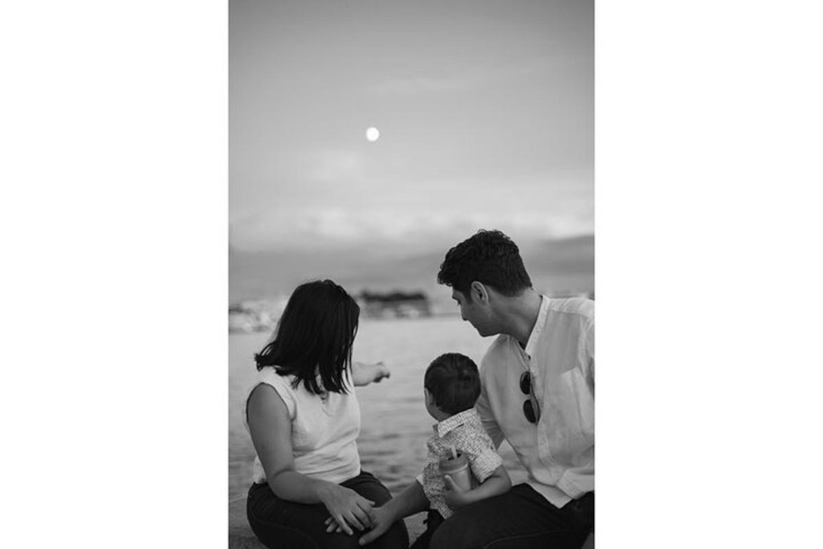 a family sitting on the beach with their child