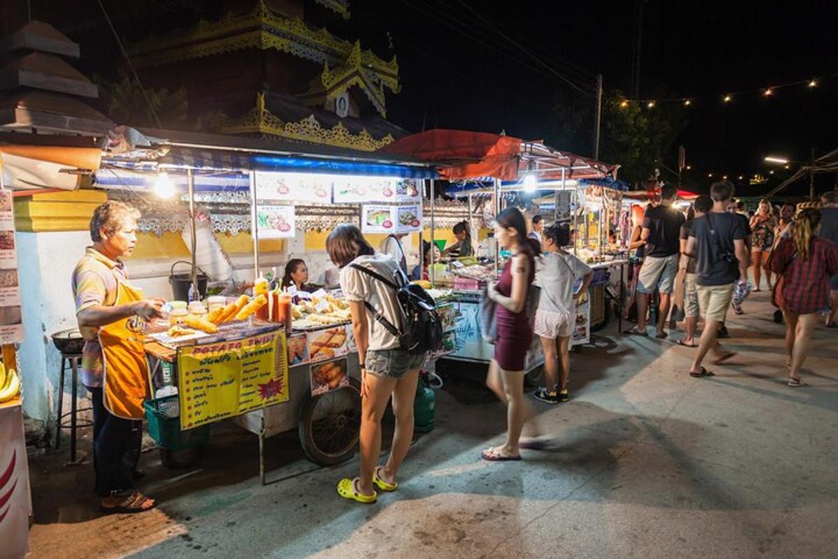 un gruppo di persone in piedi attorno a una bancarella di cibo di notte
