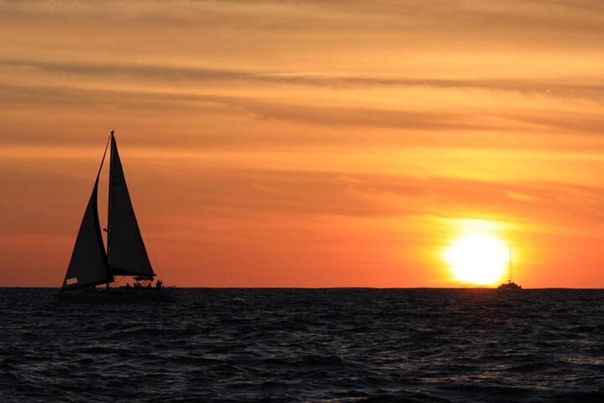 a sail boat in the ocean at sunset