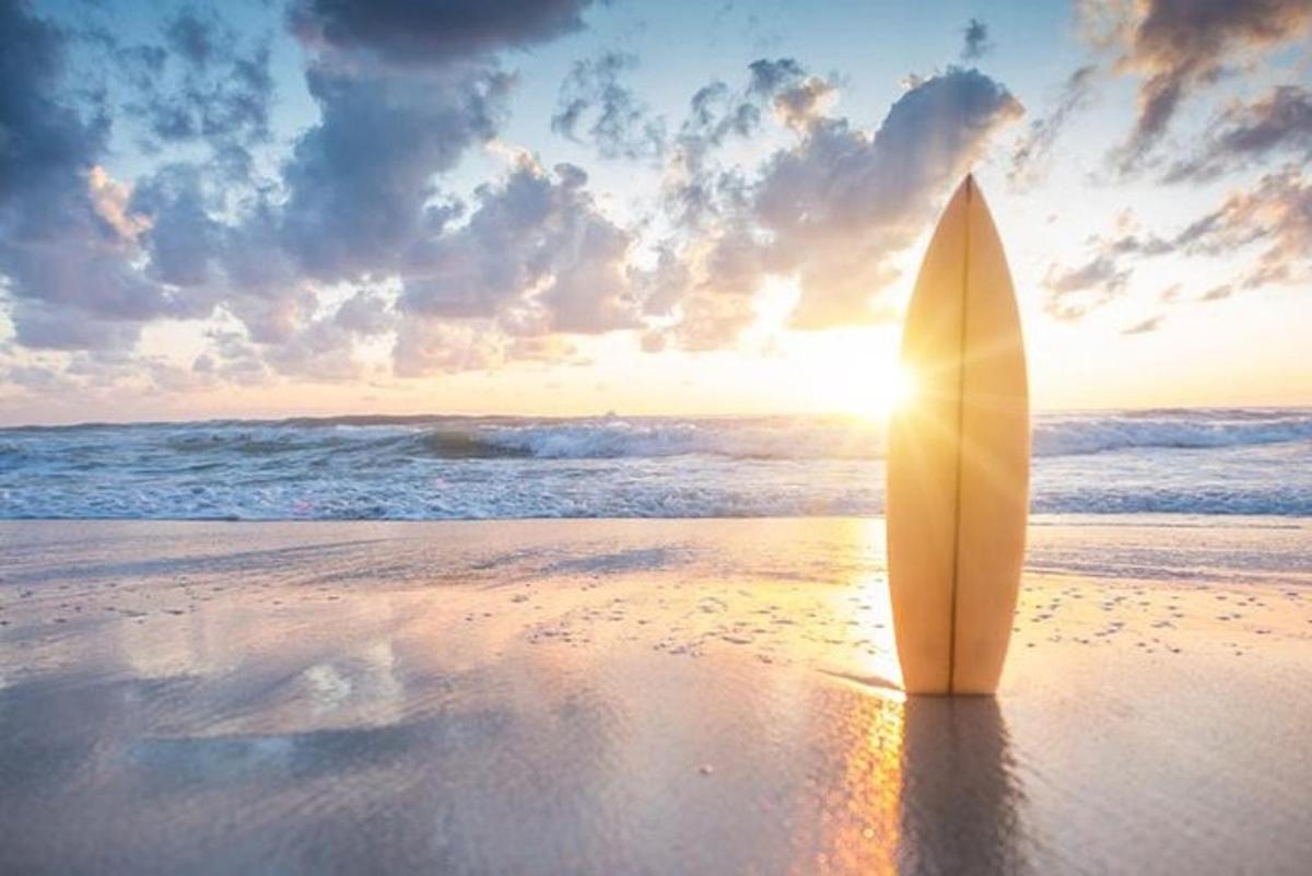 papan luncur yang duduk di pantai dengan matahari terbenam