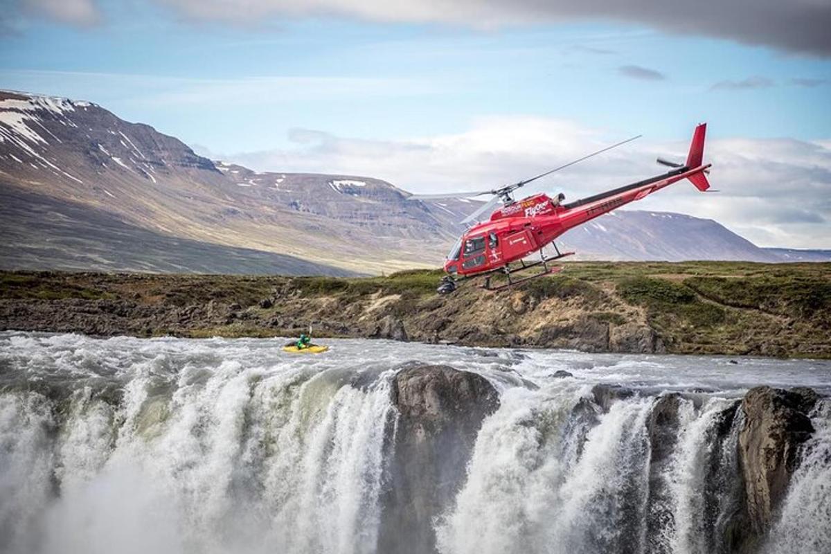 Egy piros helikopter repül egy vízesés felett