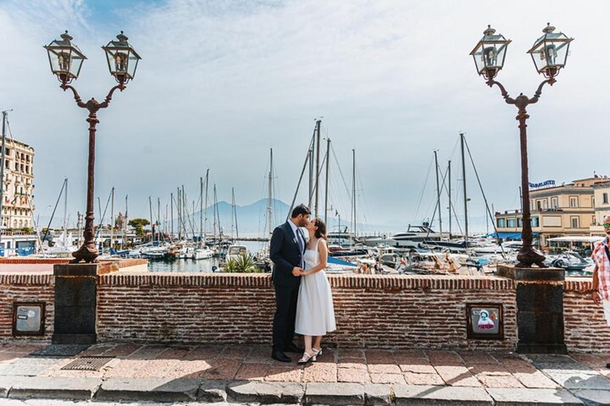 una sposa e uno sposo in piedi su un muro di mattoni vicino a un porto turistico