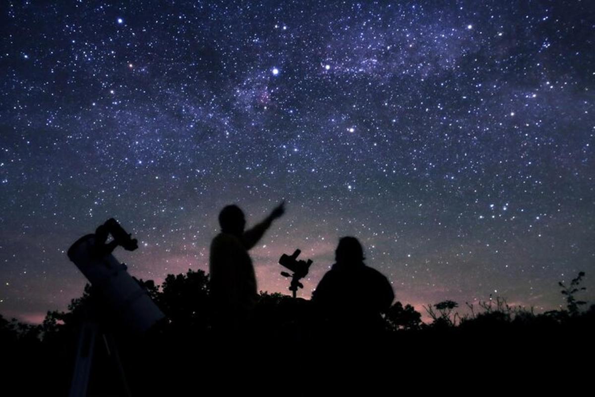 a group of three people looking up at the stars